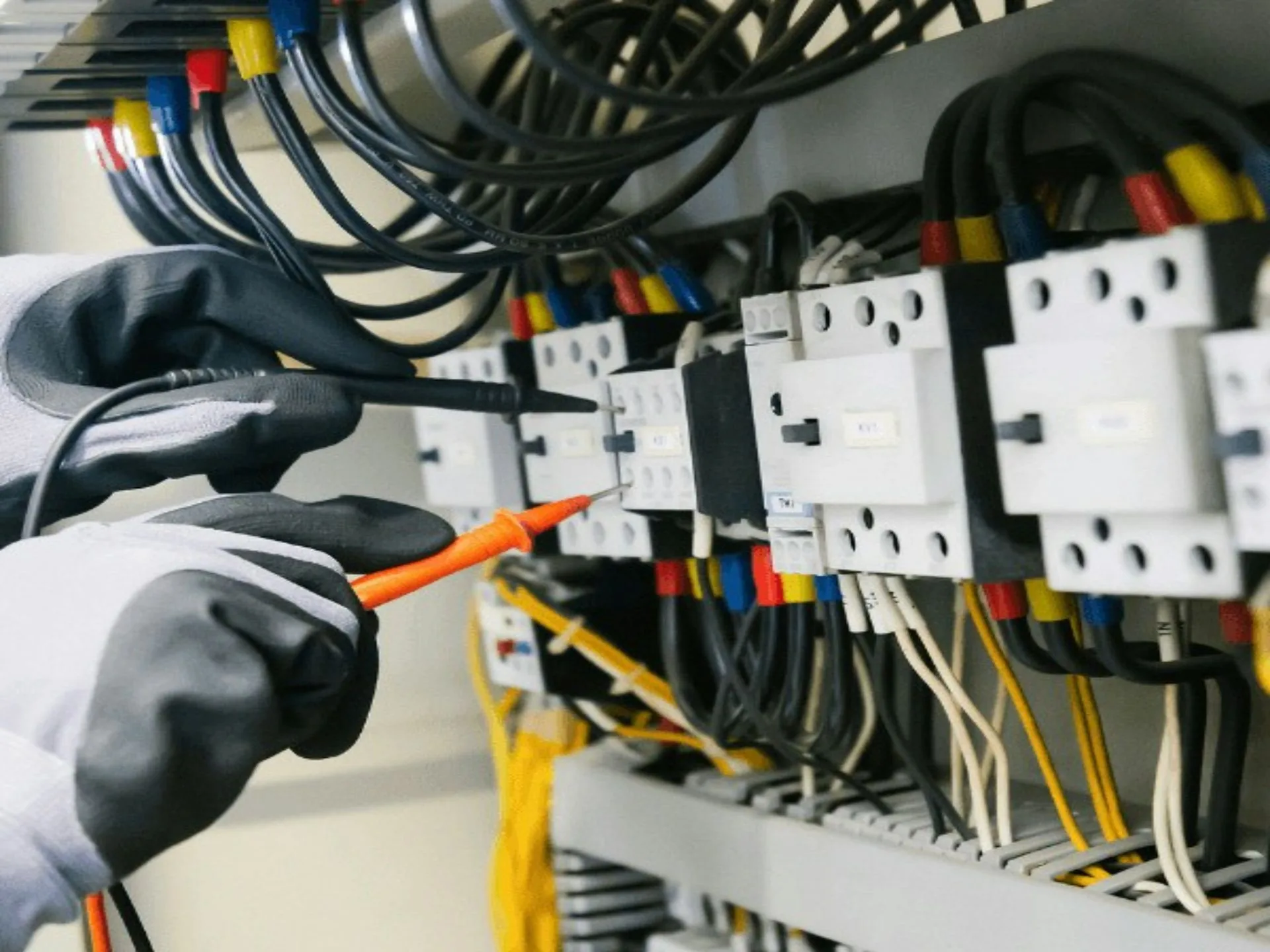 Technician taking measurements on an electrical panel